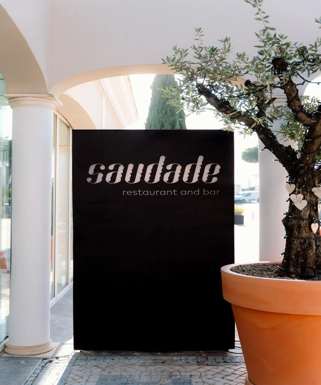 Entrada do Saudade com letreiro e oliveira